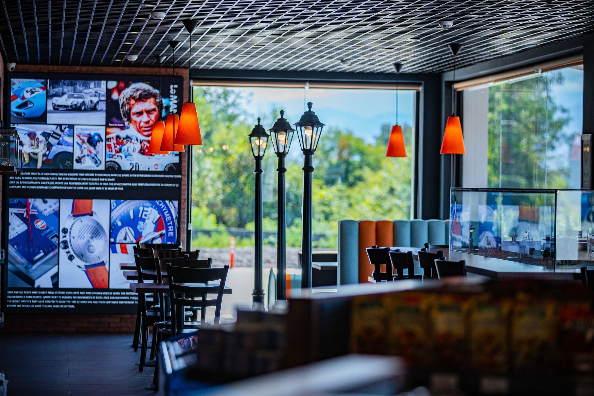 Магазин имеет спортивное кафе – в дизайне интерьера стилизованные диваны с основаниями из топливных бочек и фотографии легендарного актёра и гонщика Стива МакКуина